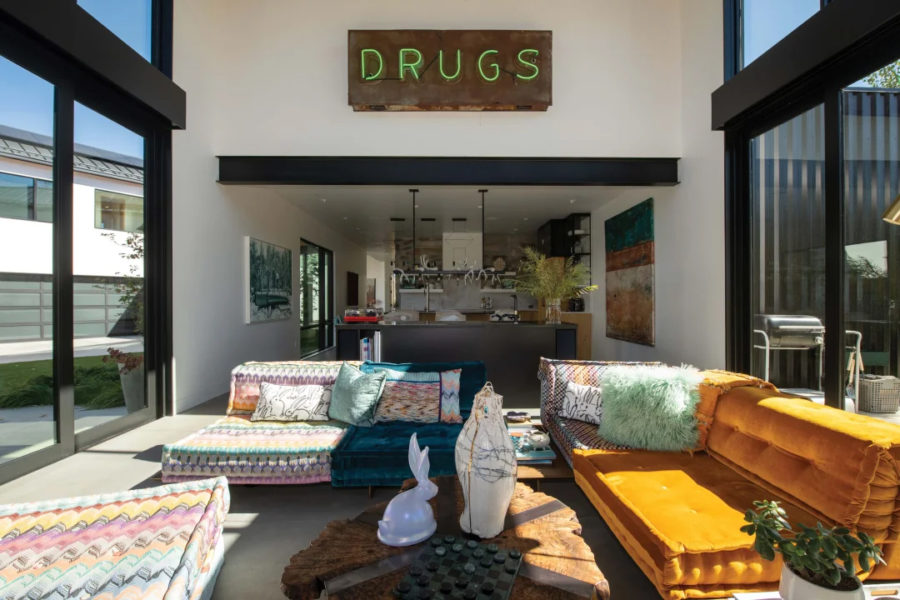 The living room features a 16-foot vaulted ceiling in vertical grain cedar. A steel fin and louver system offers protection from the sun while allowing filtered light to spill through the windows for a clean and expansive space. The neon “DRUGS” sign is an antique pharmacy sign from the Midwest. Rabbit sculpture by Hunt Slonem. Sofa by Missoni for Roche Bobois.