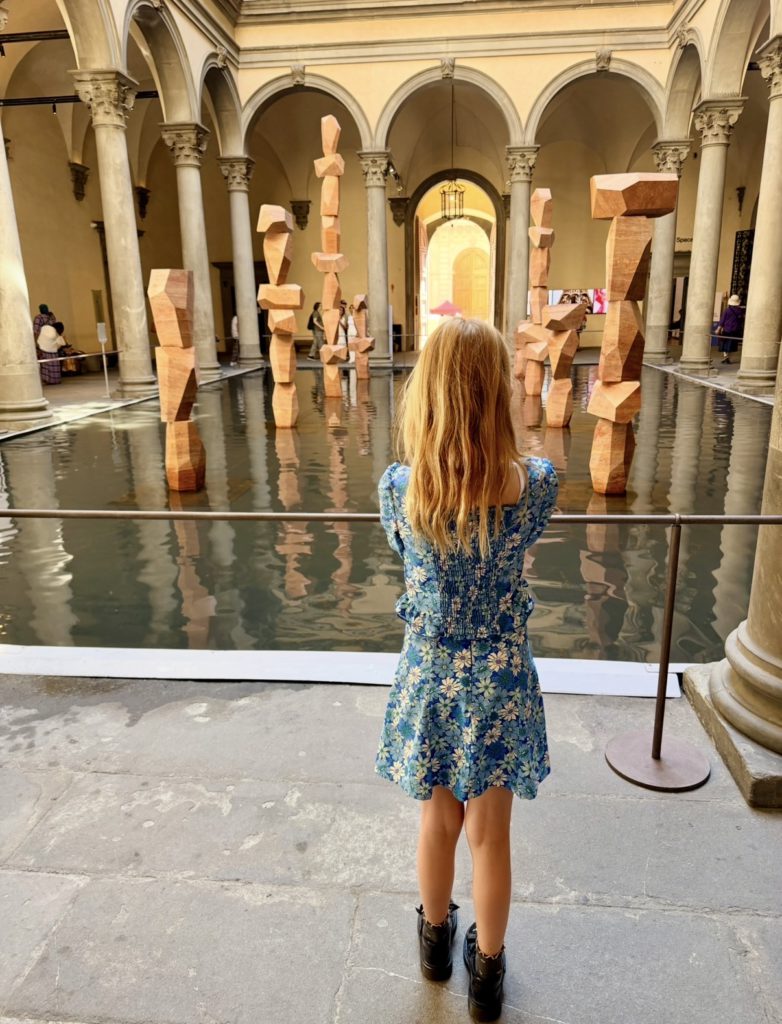 Inside the museum is a sculpture installation. The water and fish installation at Palazzo Strozzi in Florence is titled "There Are Other Fish In The Sea" by the Danish art collective SUPERFLEX. The installation transforms the Renaissance courtyard into an immersive underwater landscape with large, pink travertine columns emerging from a pool of water, serving as future habitats for marine life -- a future imagined due to ocean level rising.